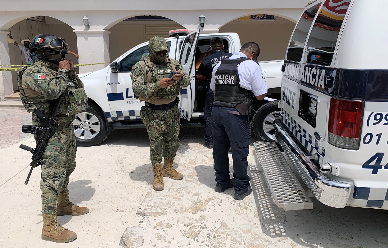 EDITORS NOTE: Graphic content / Members of the Mexican Navy are seen outiside of an ambulance carrying a tourist injured during a shooting in the tourist area of Playa Tortugas in Cancun, Quintana Roo state, Mexico on June 11, 2021. - Two waiters died in the shooting. (Photo by ELIZABETH RUIZ / AE / AFP)