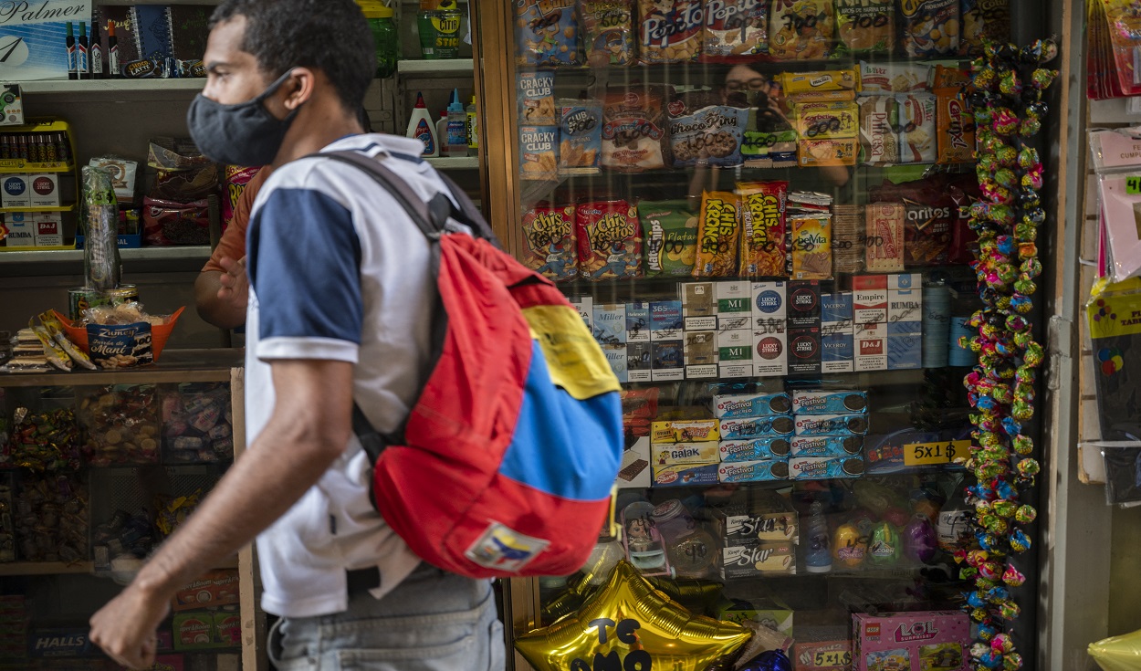 A passer-by walks by a kiosk selling, among other things, cigarettes manufactured in Colombia, China or other countries, some of which are allegedly smuggled into Venezuela through land borders and are being sold in the historic centre of the capital, in Caracas on February 19, 2021. - Though smuggling is not a new phenomenon in Venezuela it has skyrocketed in recent years amid the deep crisis, with a minimum wage of less than $ 1 a month. (Photo by Yuri CORTEZ / AFP)
