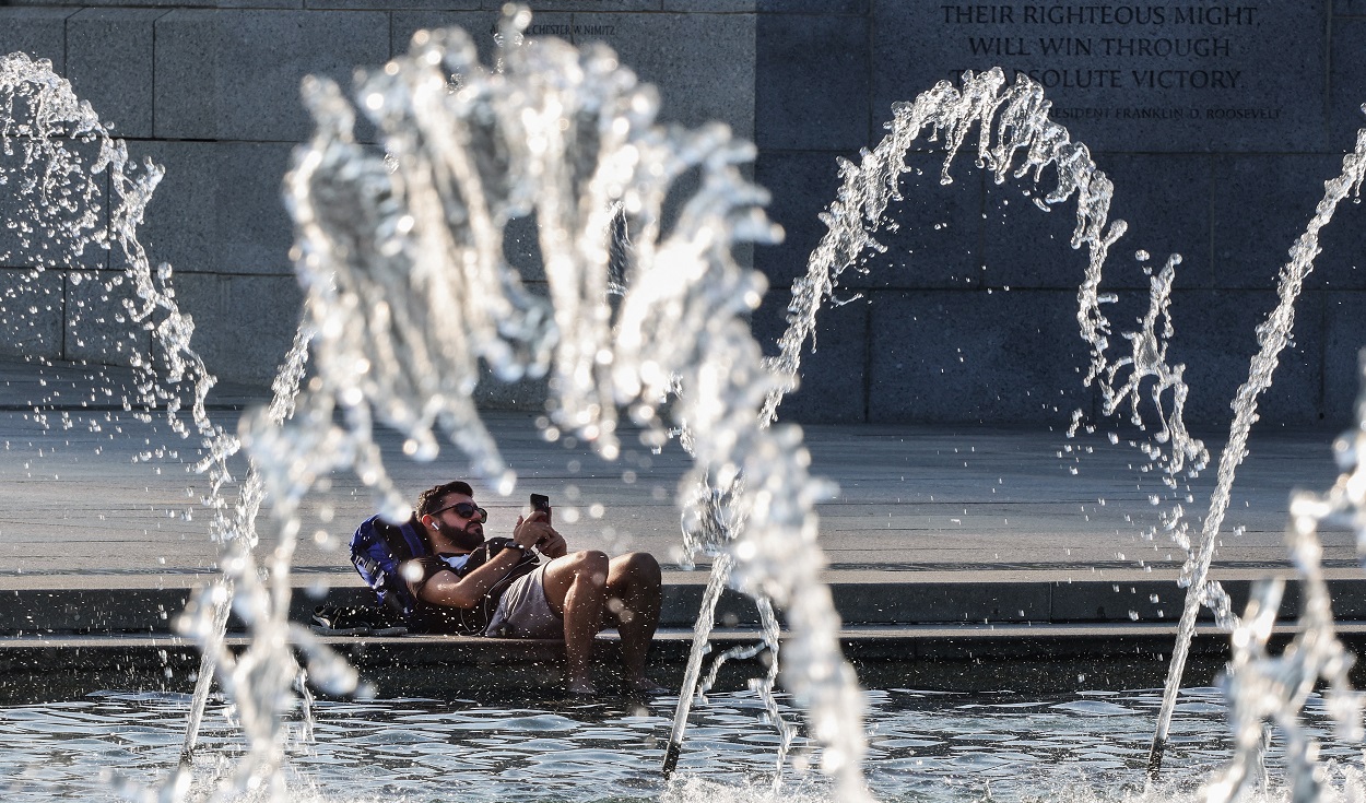 WASHINGTON, DC - AUGUST 13: A person cools off in the fountain at the World War II Memorial as temperatures are expected to reach near 100 degrees Fahrenheit on August 13, 2021 in Washington, DC. The DC metropolitan region is under a heat advisory as a third day of extreme heat and humidity hits the nation's capital.   Kevin Dietsch/Getty Images/AFP (Photo by Kevin Dietsch / GETTY IMAGES NORTH AMERICA / Getty Images via AFP)