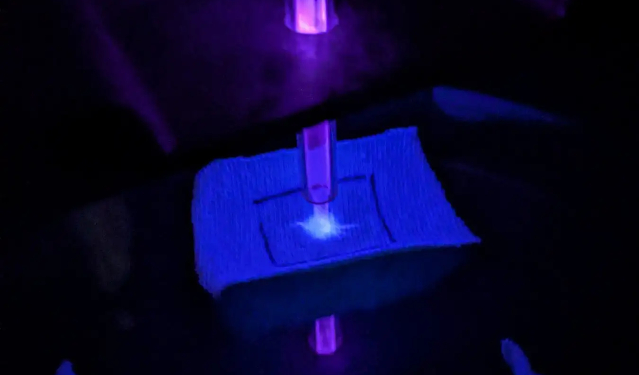 Un trozo de tela de camisa blanca siendo limpiado con plasma frío. Foto: University of Alabama
