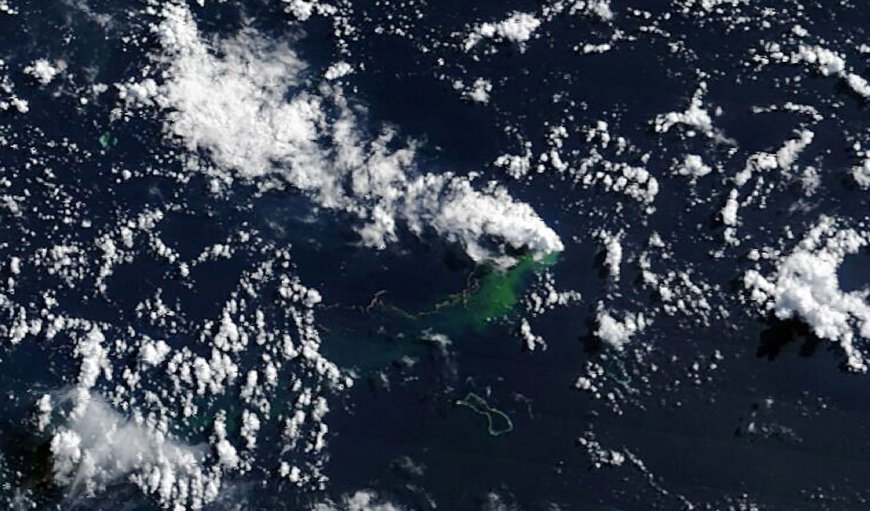 Piedra pómez flotante y agua verdosa y descolorida se extienden hacia el suroeste desde el lugar de la erupción, mientras una columna volcánica blanca se desplaza. Foto: NASA
